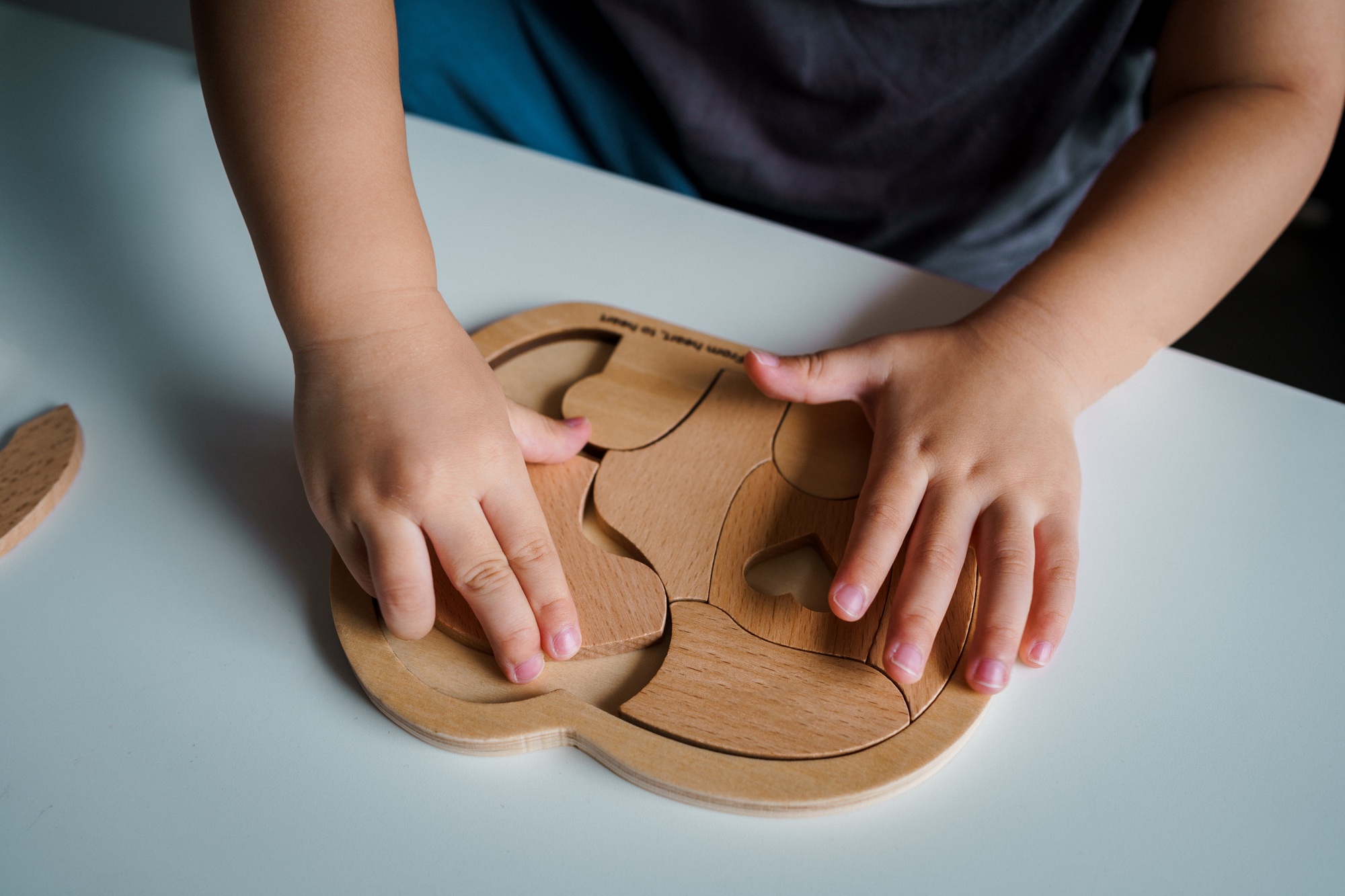 A child is playing with wooden puzzles with hands close up.